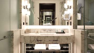 A modern bathroom with a marble vanity, a large mirror, and a patterned floor.