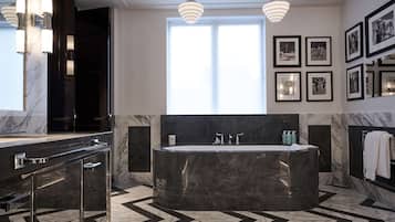 A modern bathroom with a large freestanding bathtub, marble flooring, and wall-mounted lighting.