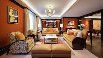 A spacious living room with a large ottoman, two sofas, a coffee table, and a bookshelf.