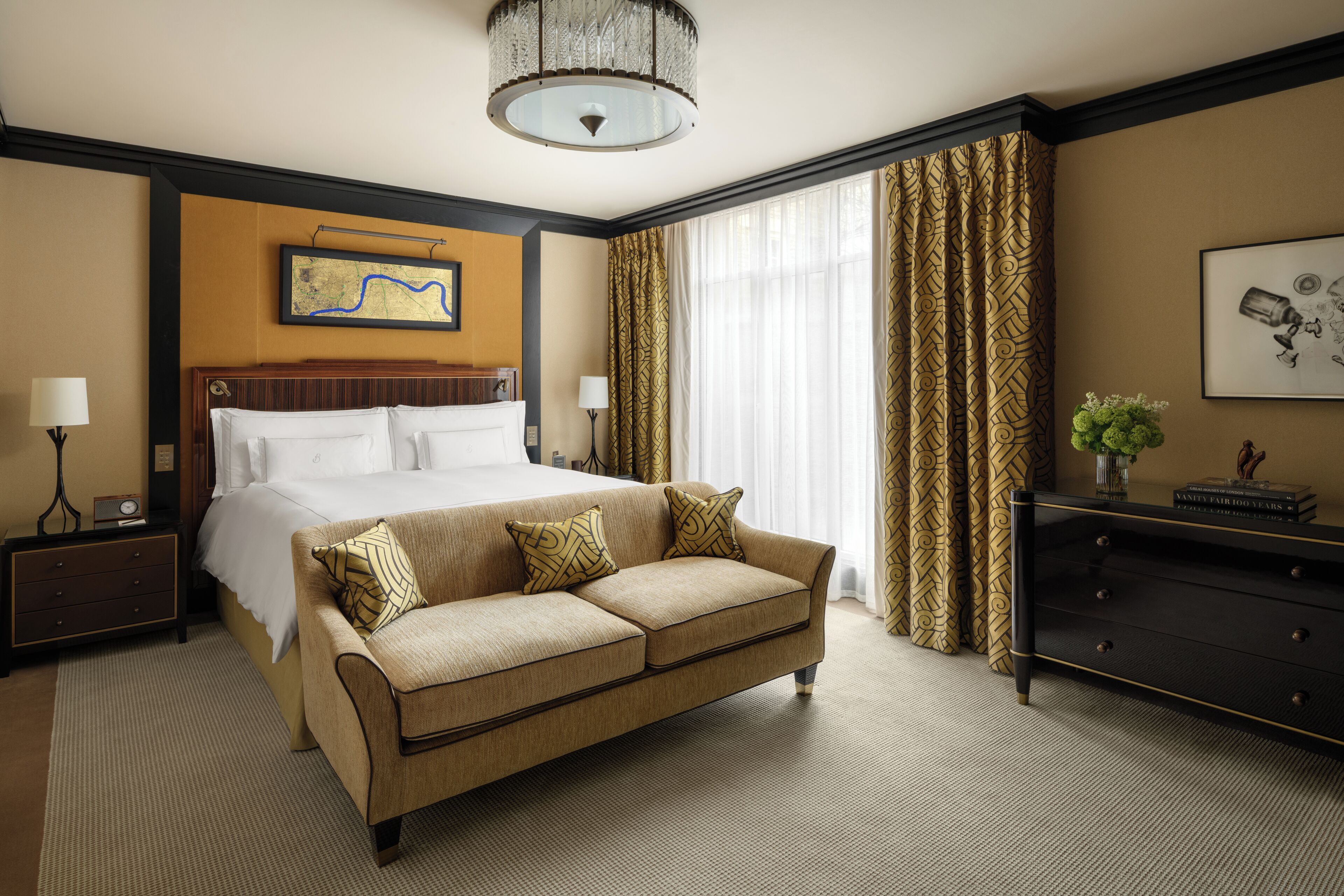 A hotel room with a large bed, a sofa, a dresser, and a chandelier.