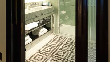 A modern bathroom with a glass shower enclosure, a marble vanity, and a patterned floor.