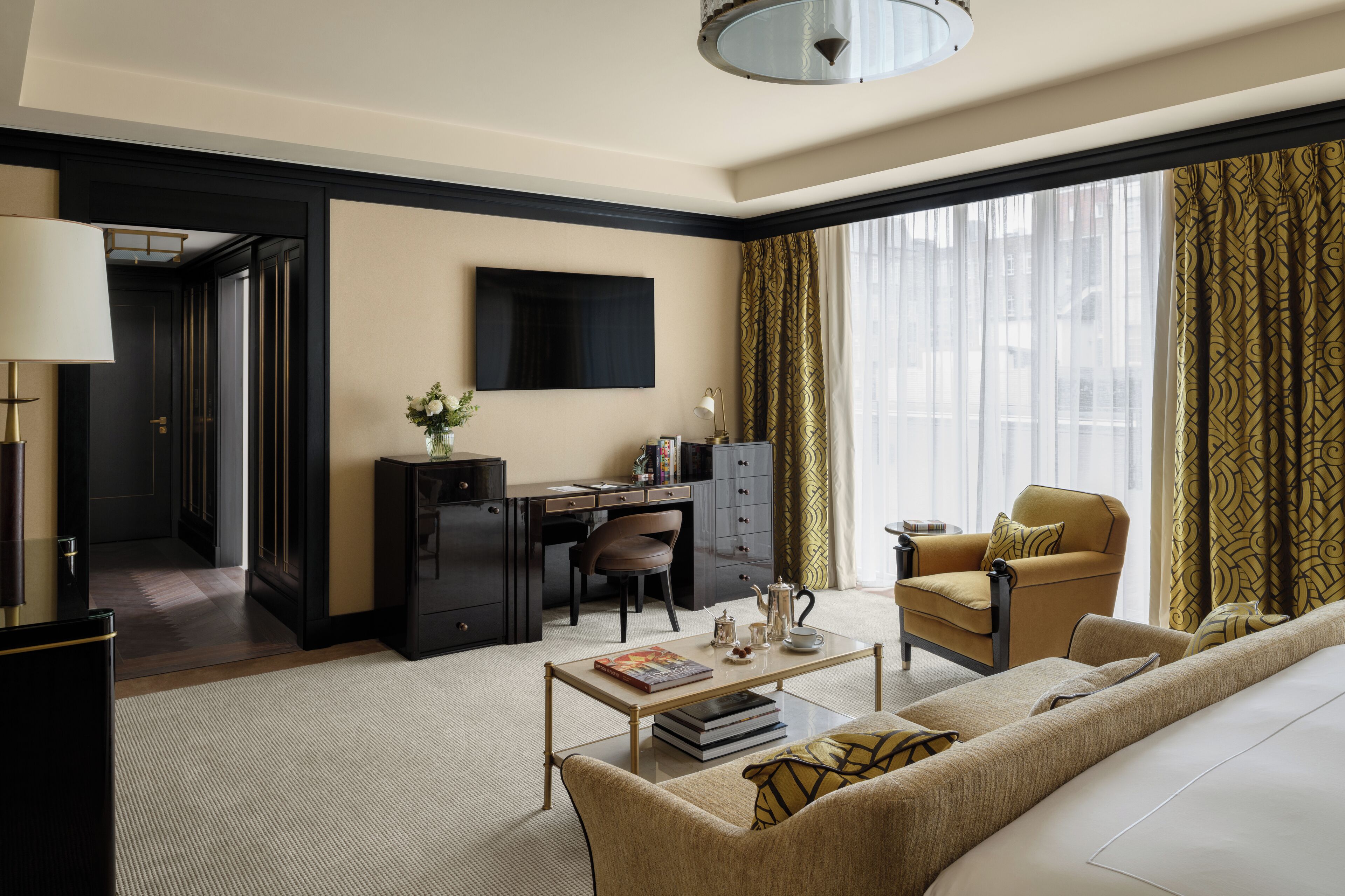 Une chambre d’hôtel moderne équipée d’un canapé, d’un fauteuil, d’un bureau et d’un téléviseur à écran plat.