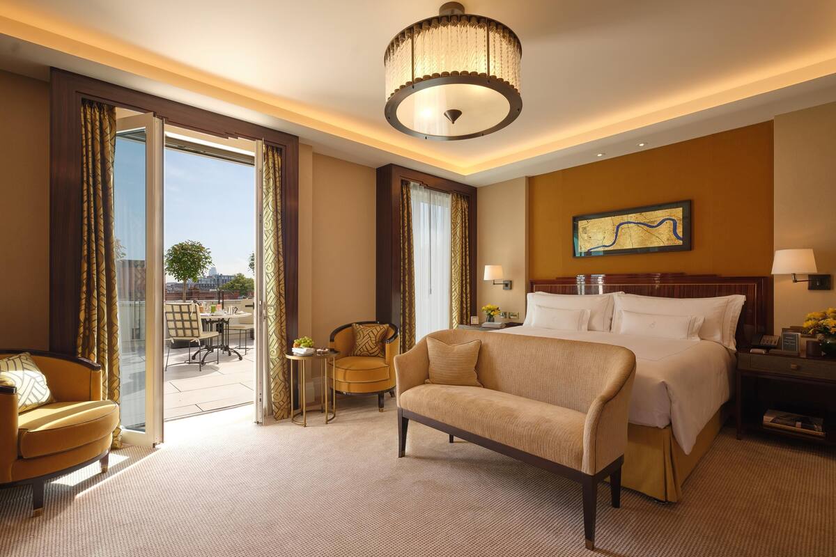 Ein Hotelzimmer mit Bett, einer Couch, einem kleinen Tisch mit Vase, einer Lampe und Blick auf die Stadt.