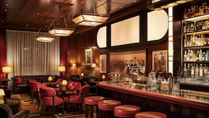 A bar area with a bar counter, stools, and a variety of bottles. - The Beaumont Mayfair (London)