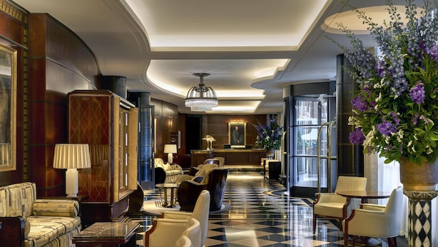 A lobby with a checkered floor, seating areas, a reception desk, and a large chandelier. - The Beaumont Mayfair (London)