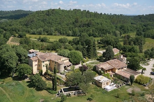 Una finca rural con varias construcciones rodeada de exuberante vegetación y un viñedo.
