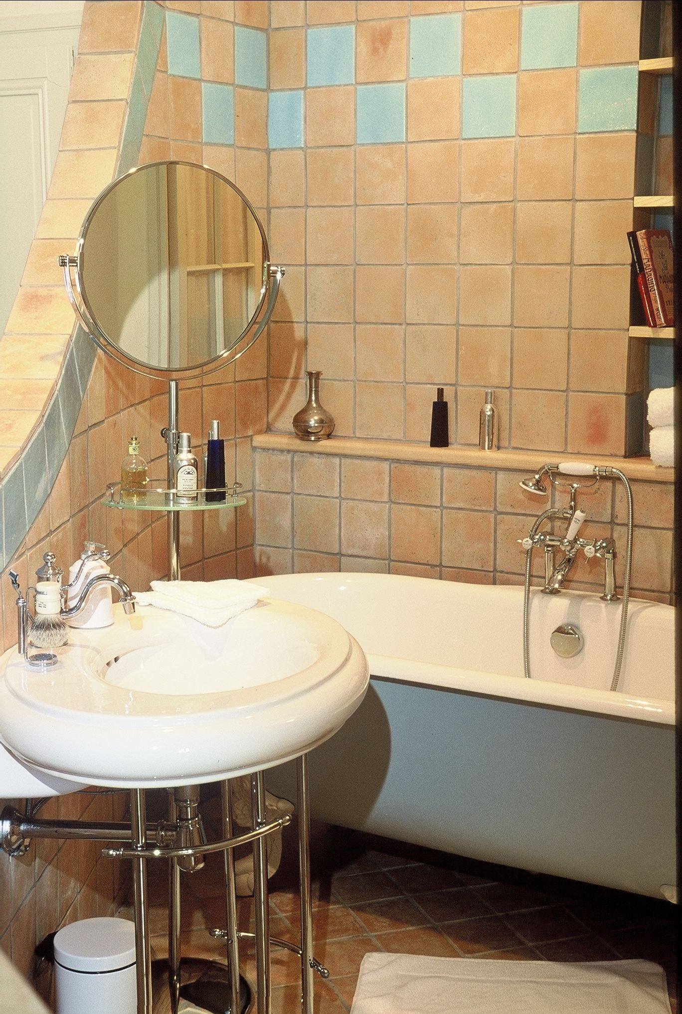 Ein Badezimmer mit rundem Spiegel, Waschbecken und Badewanne.