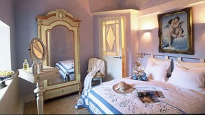 A bedroom with a large mirror, a bed with a blue and white striped bedspread, a white door, and a painting on the wall. - Une Campagne en Provence (Bras)