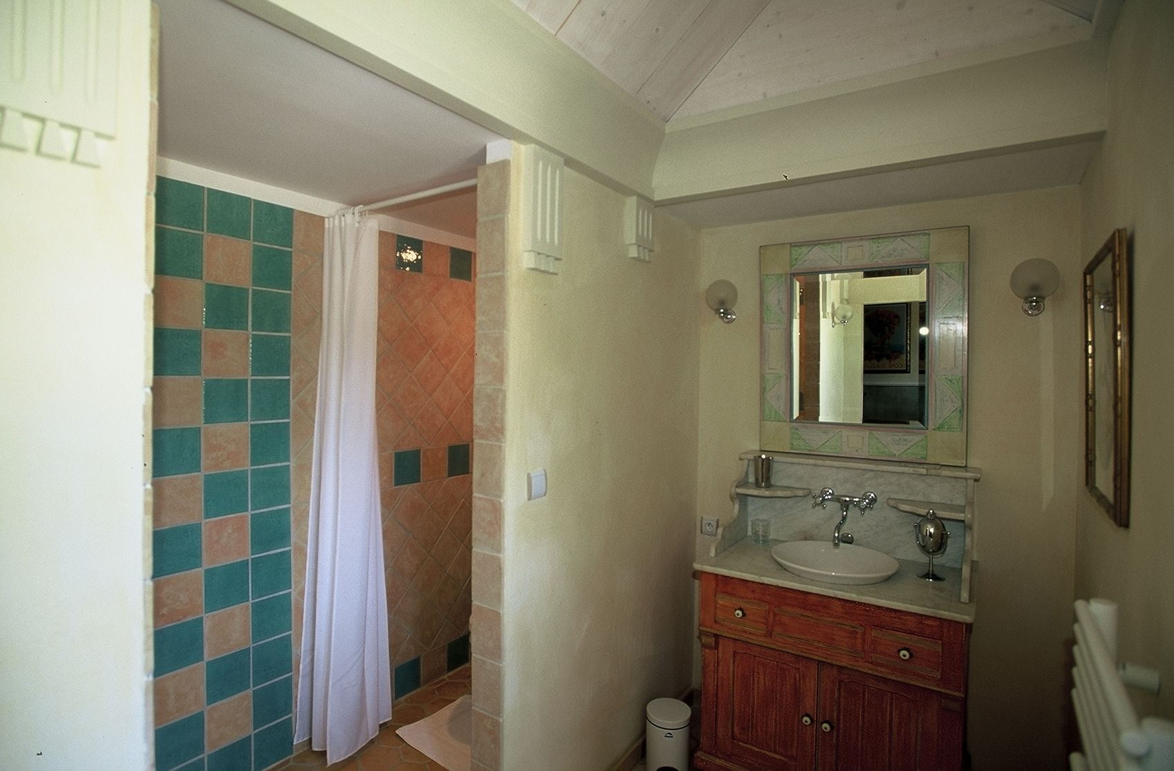 Un bagno con zona doccia piastrellata, un lavandino con specchio e un armadietto.