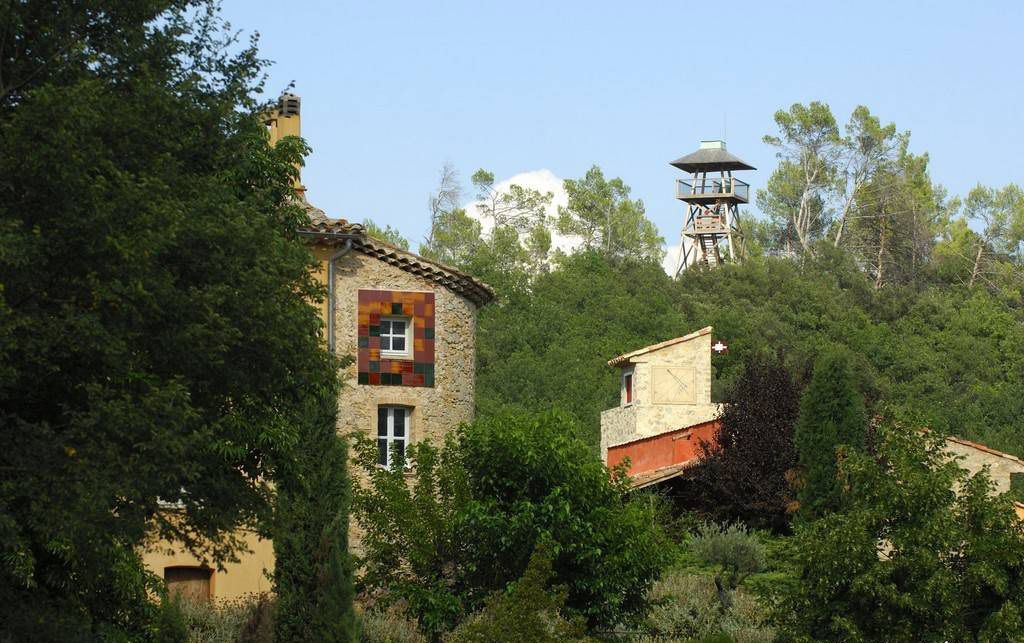 A rustic stone building with a small window and a tower-like structure in the background.