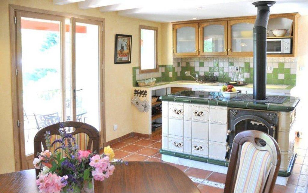 Una cucina con piano cottura, mobili e zona pranzo con tavolo e sedie.