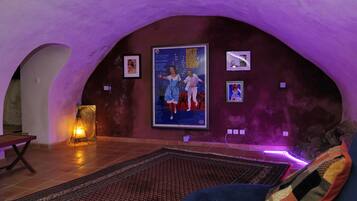 A cozy room with a large poster of 'West Side Story' on the wall, a patterned rug, and a bench.