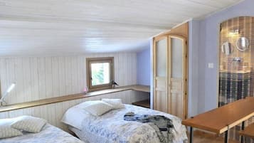 A bedroom with two beds, a wooden bench, a window, and a door.