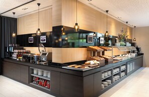 Een moderne buffetopstelling met diverse gerechten, een koffiehoek en een decoratieve vaas.