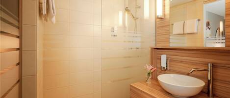 A modern bathroom with a glass shower enclosure, a wooden vanity with a vessel sink, and a large mirror.