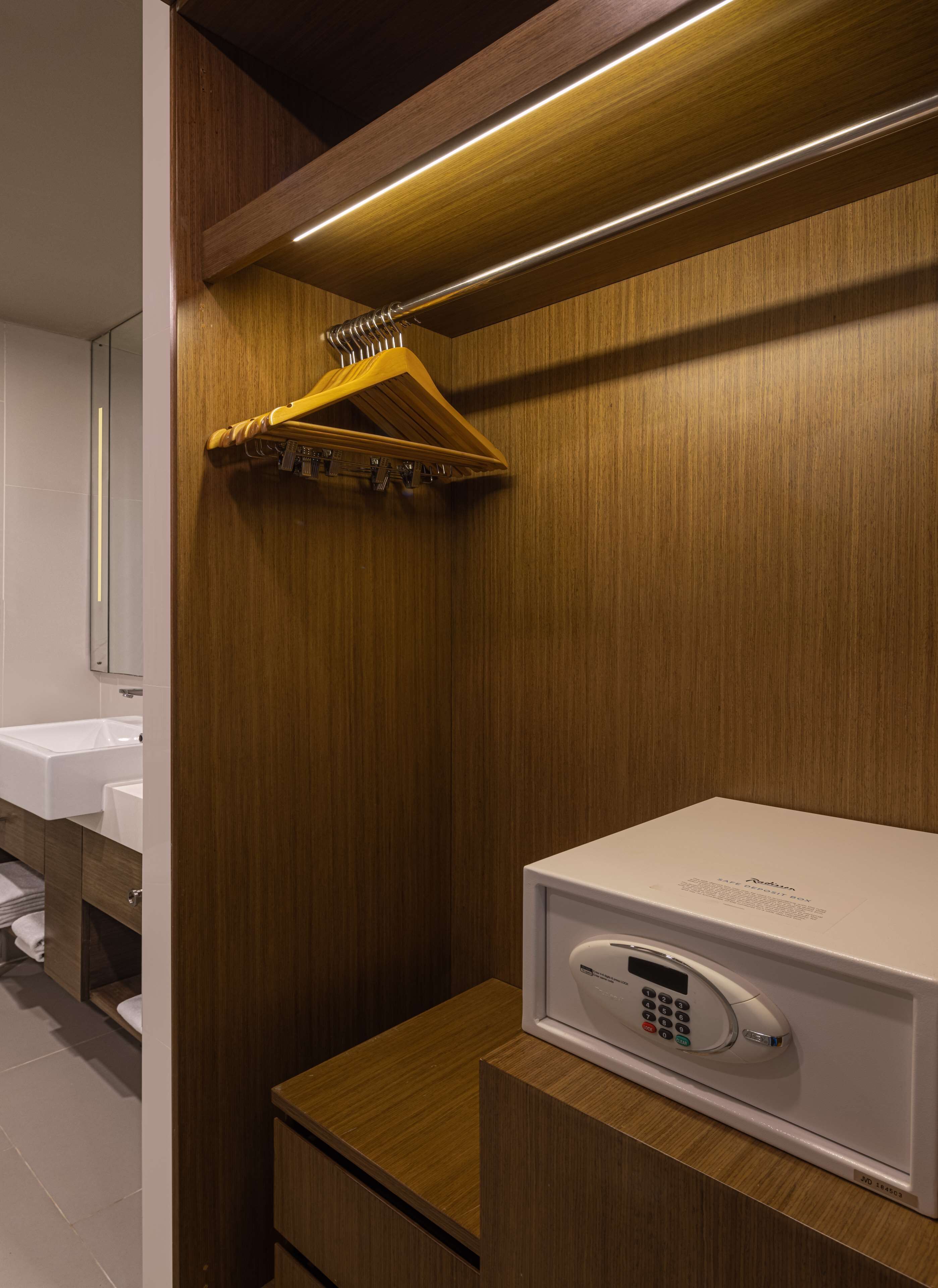 A modern bathroom with a wooden vanity, a white sink, and a built-in microwave.