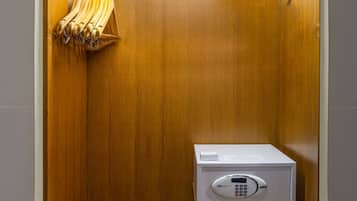A wooden closet with a metal rod rack, a microwave, and a small wooden cabinet.