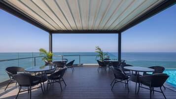 A covered outdoor seating area with a view of the ocean.