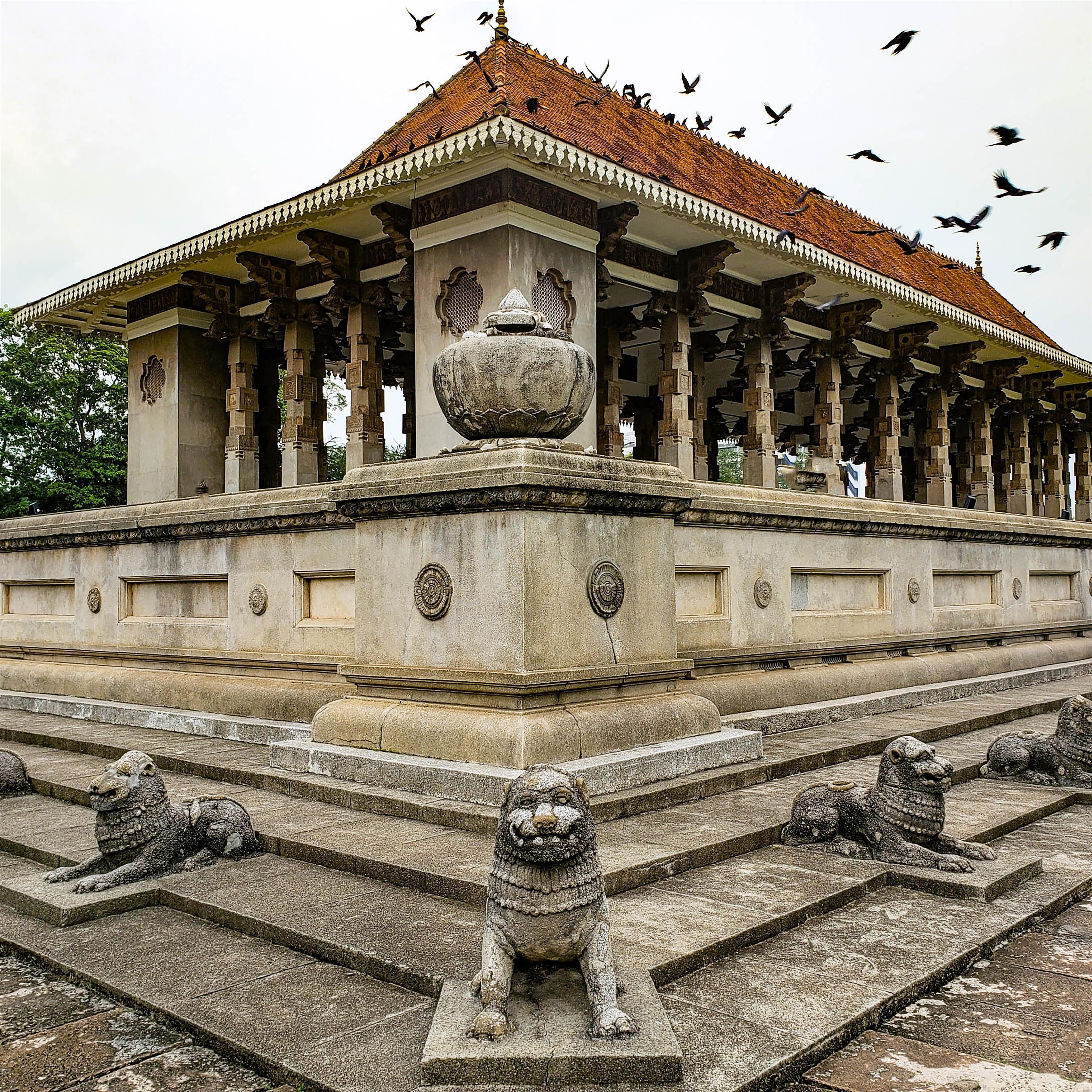 Un templo con techo de tejas, leones de piedra y aves volando.