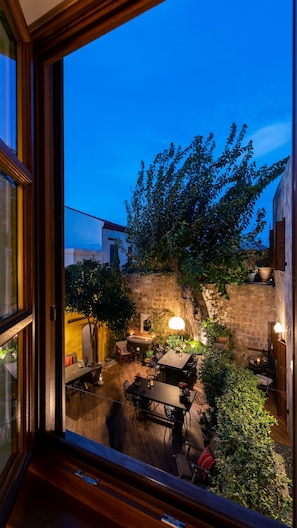 An outdoor patio area with stone walls, a wooden table, and chairs.