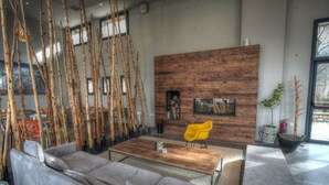 Uma sala de estar moderna com uma parede de madeira, um sofá, uma mesa de centro e uma poltrona amarela.