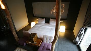 Un dormitorio con una cama grande, lámparas de noche, cabecera de madera y una ventana con cortinas.