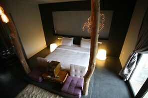 Une chambre à coucher avec un grand lit, des lampes de chevet, une tête de lit en bois et une fenêtre avec des rideaux.