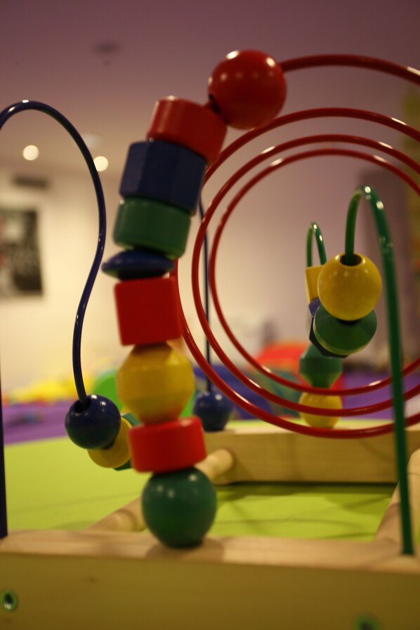A colorful wooden toy structure with rings and beads.