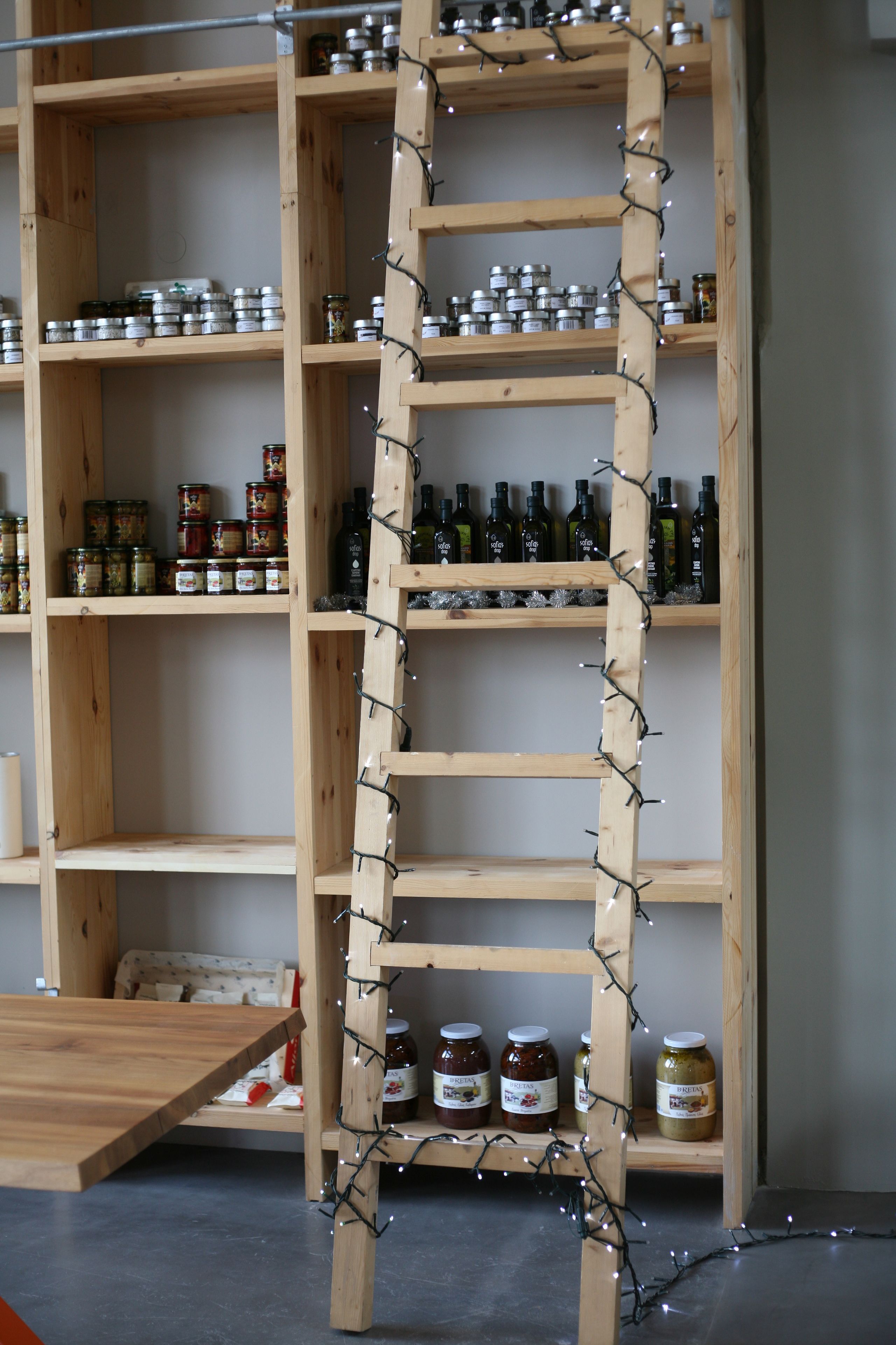 A wooden ladder with jars and bottles on shelves.