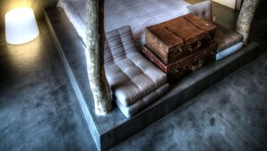Quarto moderno com uma cama grande, tronco de árvore como cabeceira e instalação de luz em formato de coração na parede.
