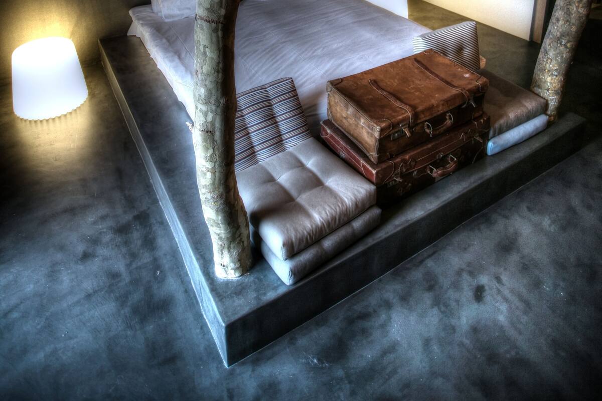 A modern bedroom with a large bed, a tree trunk as a headboard, and a heart-shaped light installation on the wall.
