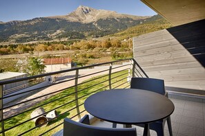 Un balcon avec une table et des chaises, donnant sur un paysage montagneux.