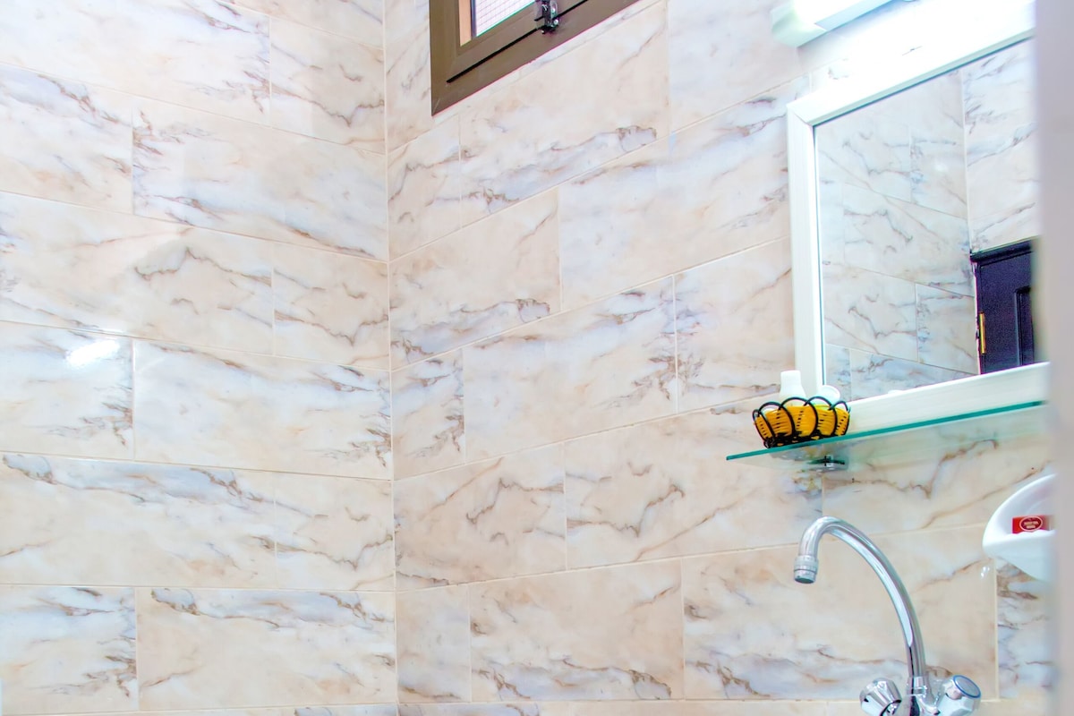Une salle de bain équipée de toilettes, d’un bidet, d’un lavabo et dont les murs sont recouverts de marbre.