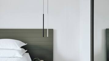A modern bedroom with a bed, bedside table, and a nightstand with a plant.