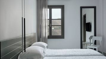 A bedroom with a bed, a window, a chair, and a TV.