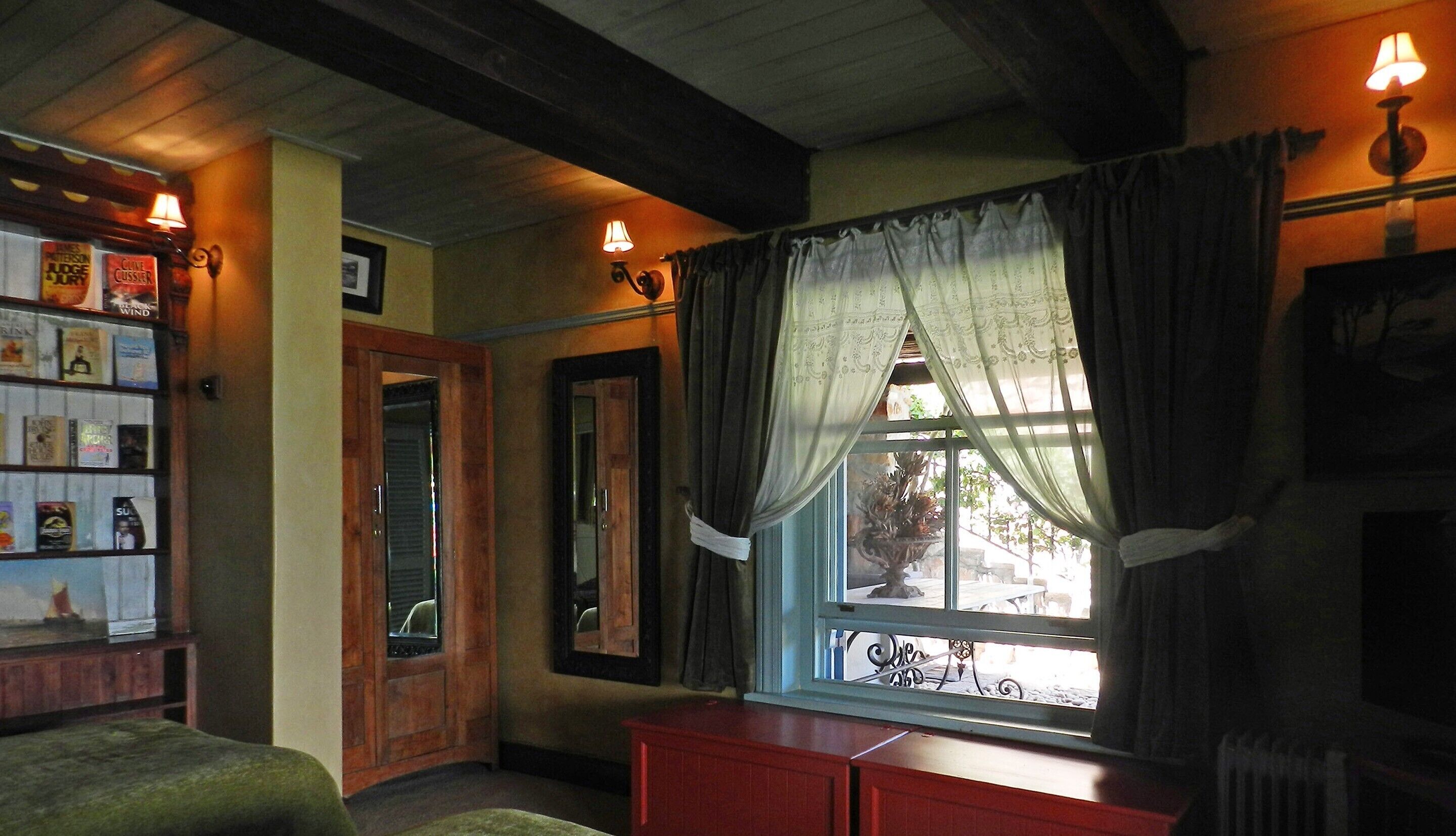 A cozy room with a wooden bookshelf, a window with curtains, and a radiator.