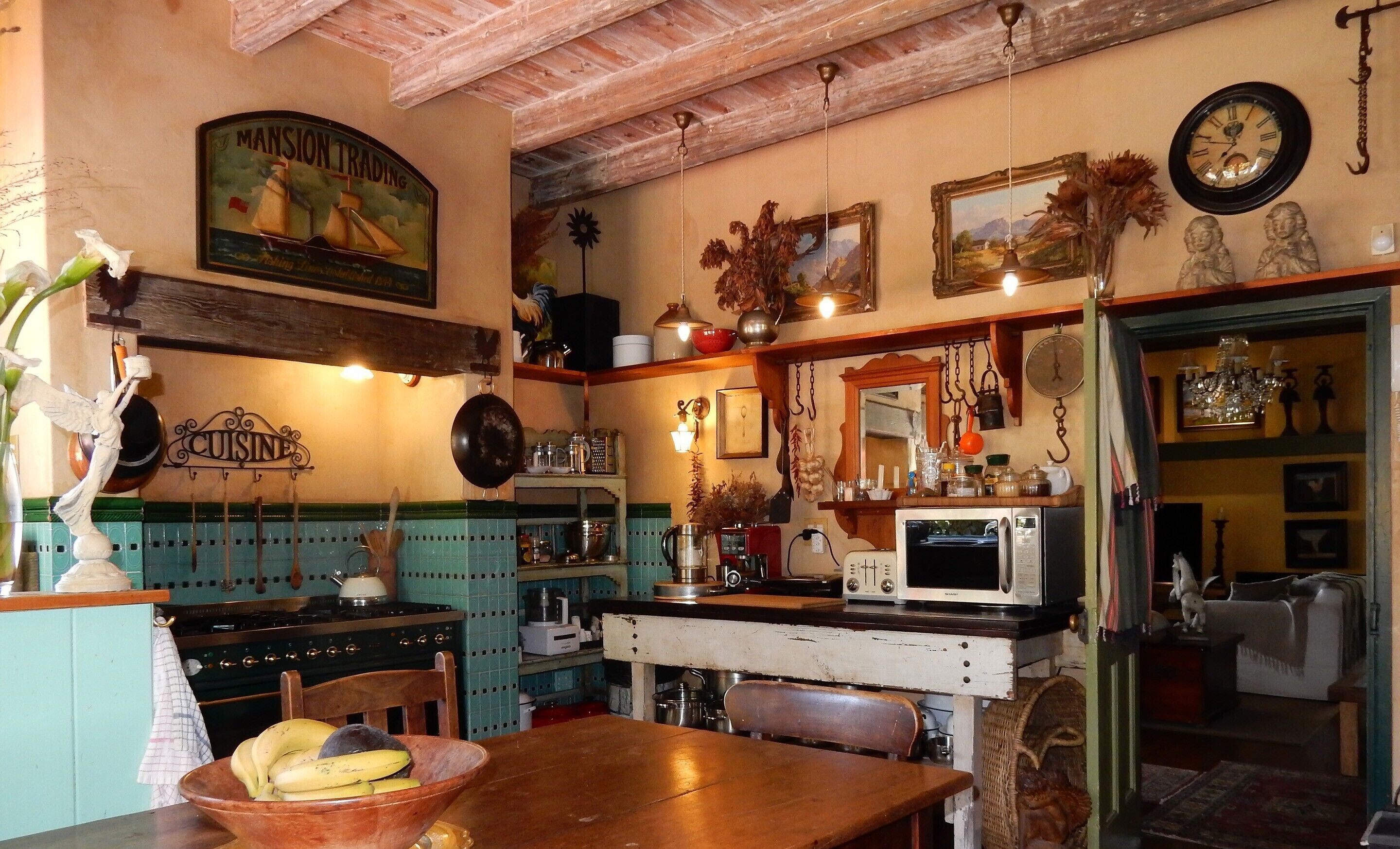 A vintage kitchen with a wooden table, a bowl of bananas, and a vintage stove.