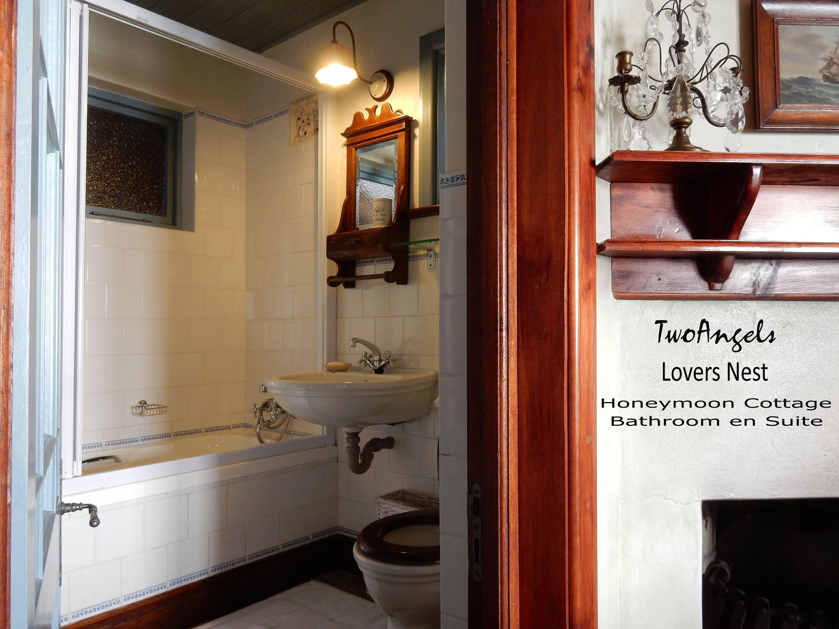 A bathroom with a bathtub, sink, and toilet. There is a mirror above the sink and a chandelier on the wall.