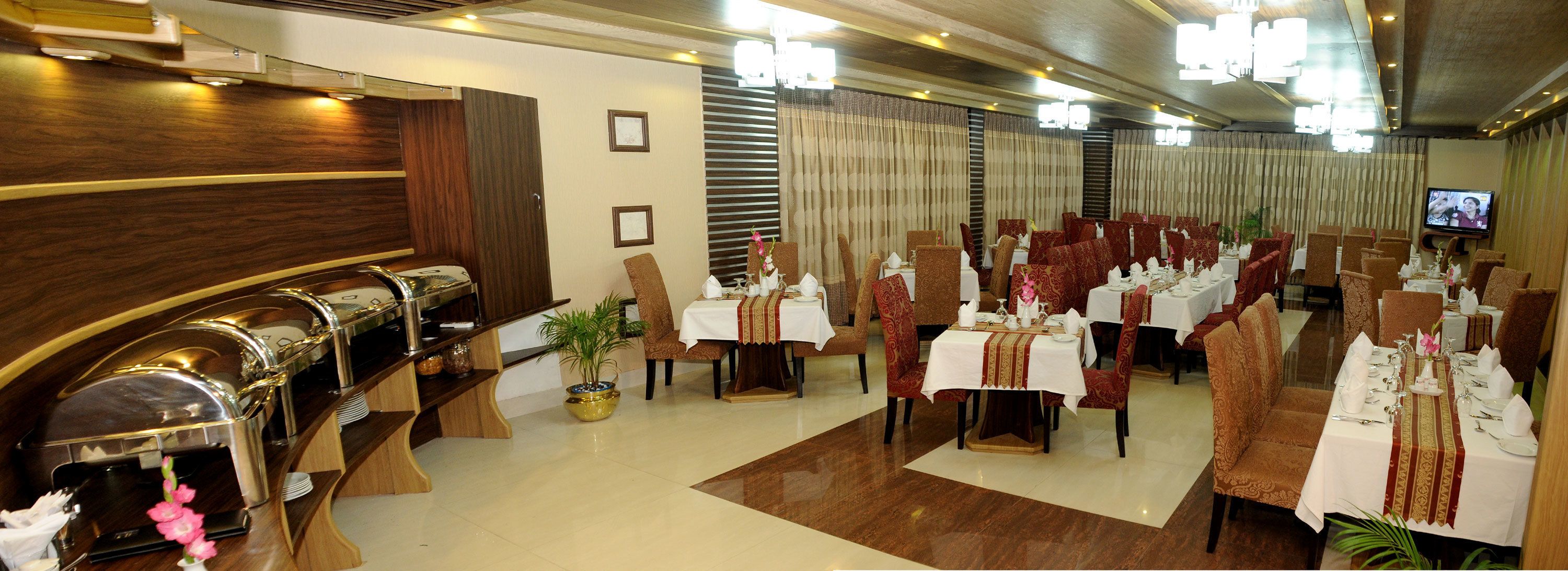 A restaurant with multiple tables, chairs, and a buffet area.