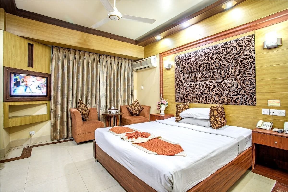 A hotel room with a bed, a TV, a desk, and a chair.