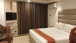Een hotelkamer met een bed, een aan de muur bevestigde televisie, een bureau en een stoel.