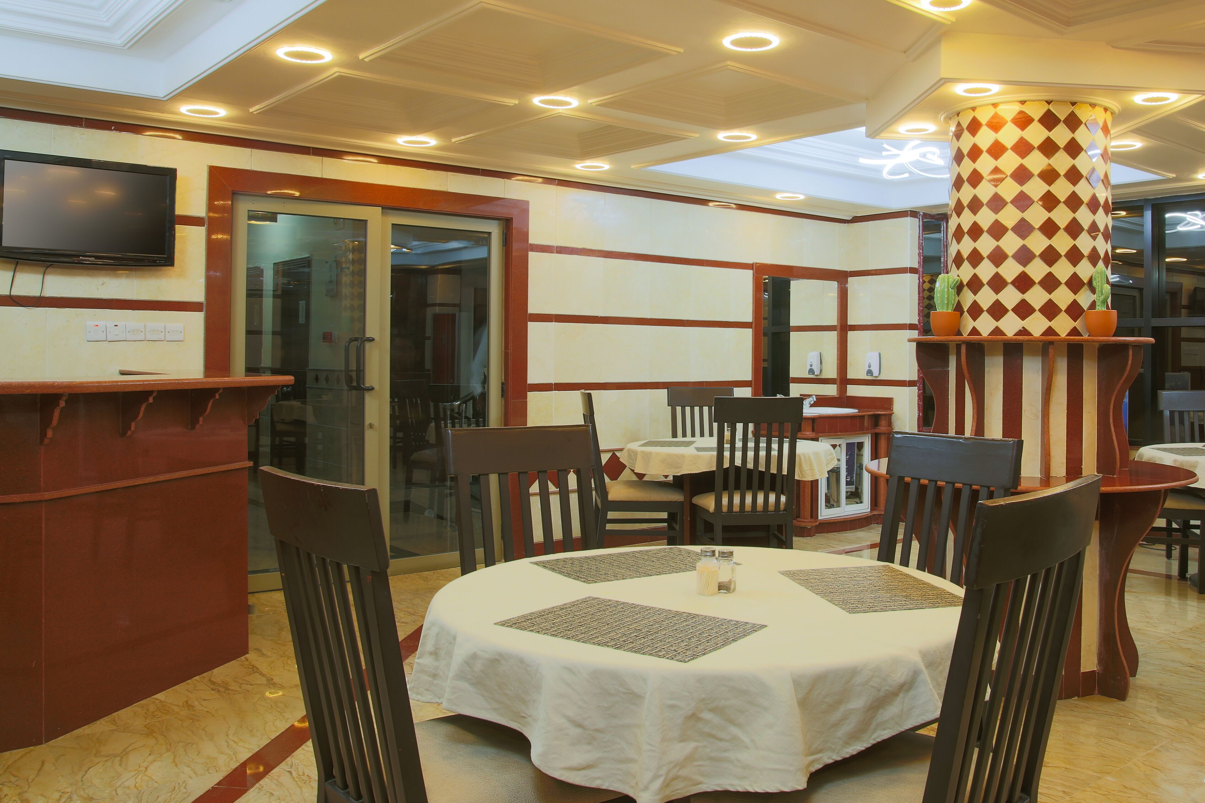 A restaurant with round tables, chairs, and a TV mounted on the wall.
