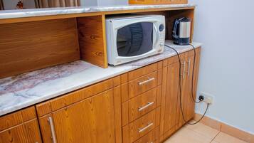 Une cuisine avec des meubles en bois, un plan de travail en marbre, un four à micro-ondes et une bouilloire.