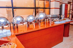 Montaje de bufé con varias estaciones de servicio de alimentos, cada una con una cubierta tipo cúpula y una bandeja metálica.