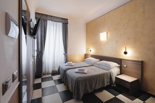 A hotel room with two beds, a checkered floor, a wooden headboard, and a nightstand.