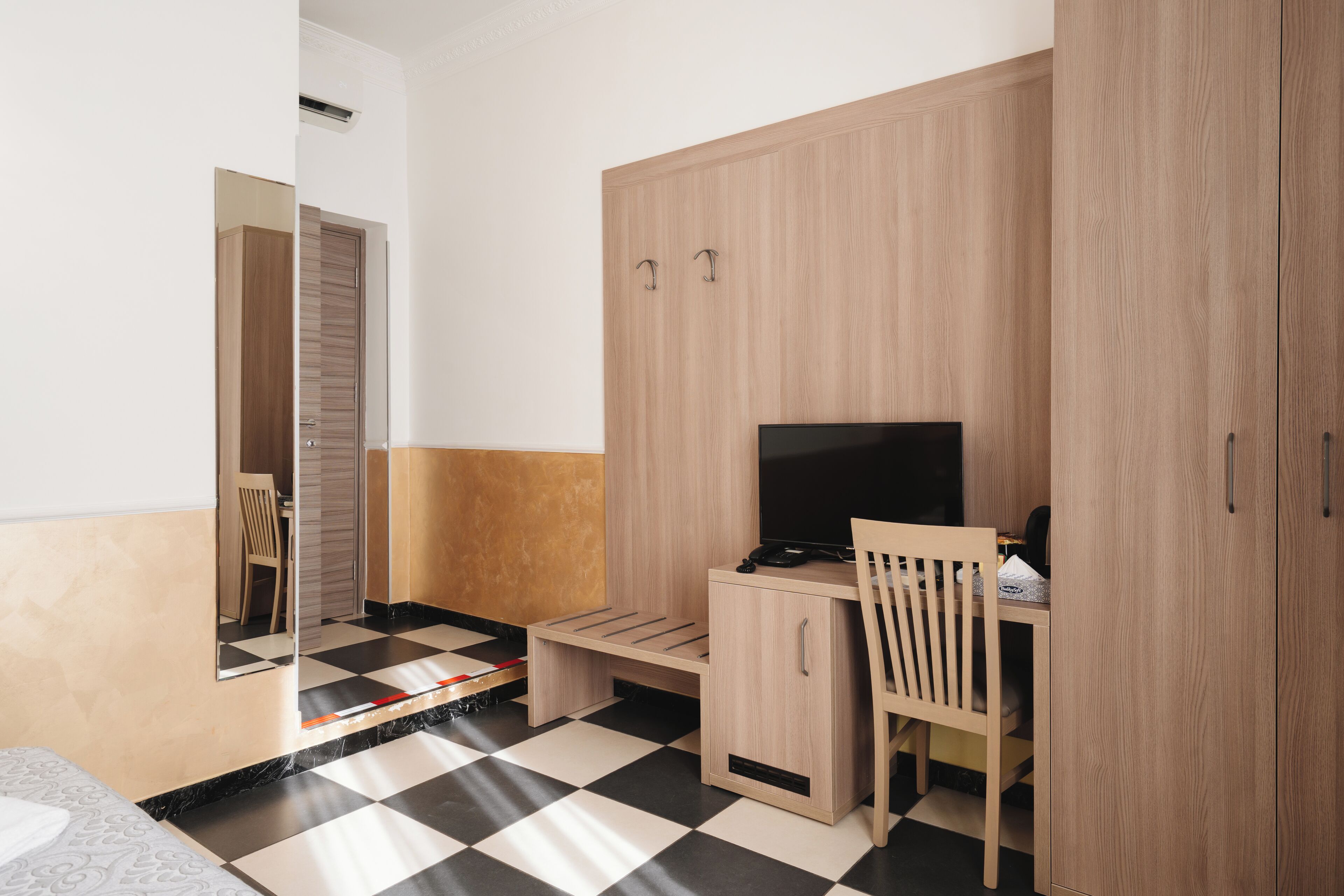A room with a bed, a desk with a chair, a TV, and a wardrobe.