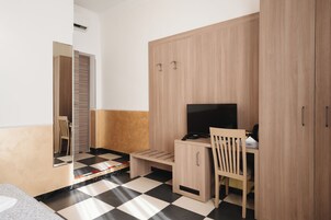 Una habitación con cama, un escritorio con silla, televisor y armario.