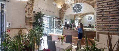 A restaurant with brick arches, a central counter, and indoor plants.