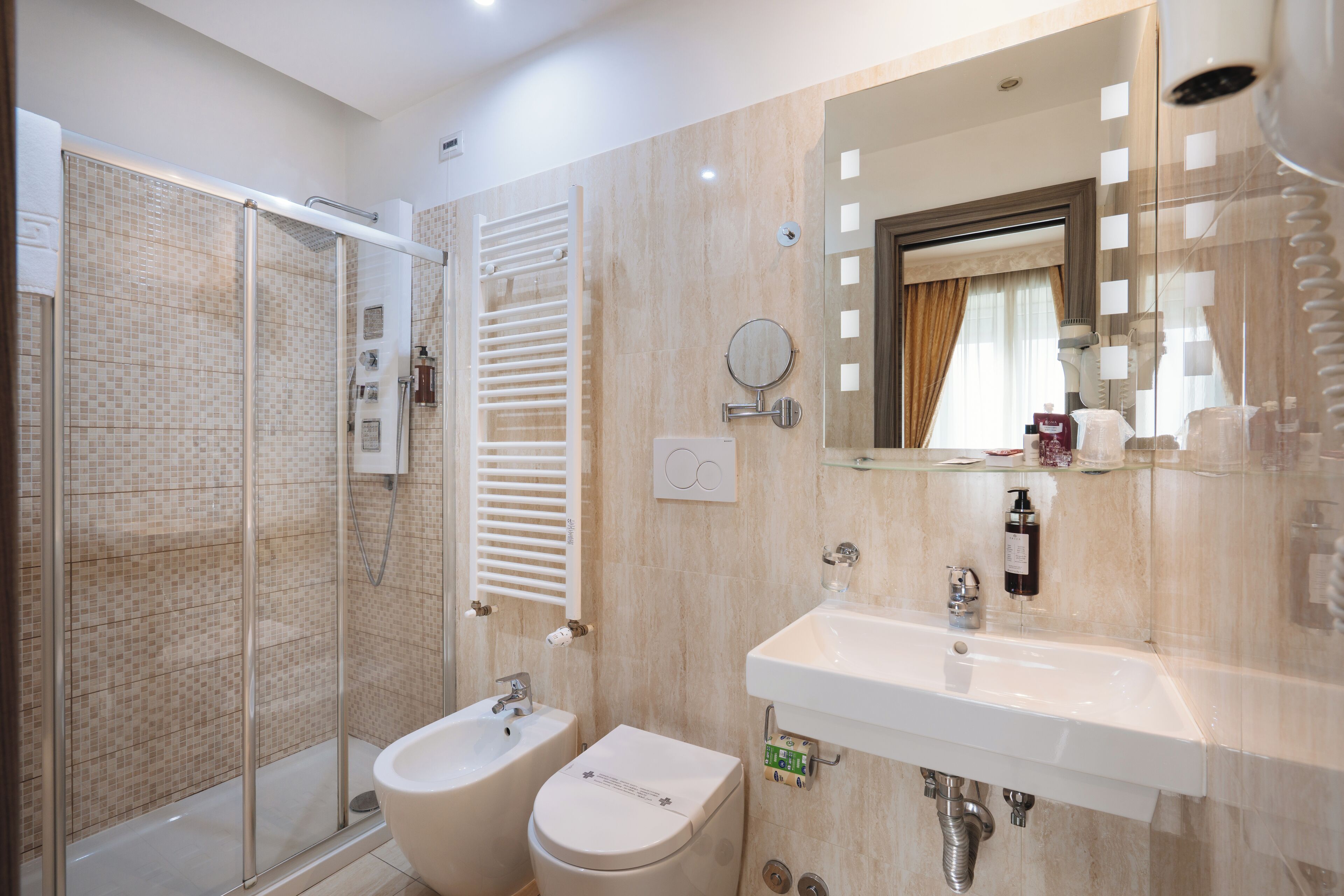 A modern bathroom with a glass shower enclosure, a bidet, a toilet, and a sink with a mirror above it.