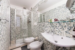 Un bagno con doccia, WC, bidet e lavandino con specchio.